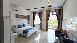 A modern hotel room with a large bed, a seating area with a chair and a table, and a view of the outdoors. - Aroma-Pool-Breakfast-Man Thai beach (Da Nang)