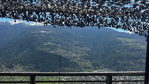 Ein Essbereich im Freien mit einem Tisch für zwei Personen, mit Blick auf eine Berglandschaft.