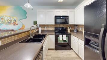 A kitchen with white cabinets, a black microwave, a black oven, and a black refrigerator.