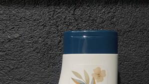 Una botella de loción Above con tapa azul, etiqueta blanca y logotipo verde.