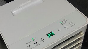 Un purificador de aire blanco, compacto y portátil con pantalla digital, múltiples salidas de aire y un logo azul en la parte inferior.