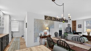 A modern kitchen with a dining area, a chandelier, and a map on the wall. - Forest Backdrop Midcoast Maine Quiet Escape 3 Bedroom Home (Dresden)