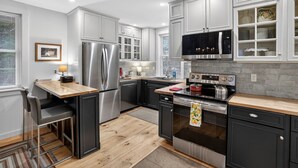 A modern kitchen with stainless steel appliances, a wooden countertop, and black cabinetry. - Forest Backdrop Midcoast Maine Quiet Escape 3 Bedroom Home (Dresden)