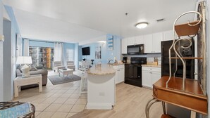A modern kitchen with white cabinets, a granite countertop island, and a built-in oven. - A Coastal Paradise - Beachfront - Gym - Pool (Myrtle Beach)