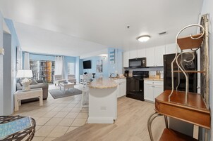 A modern kitchen with white cabinets, a granite countertop island, and a built-in oven.