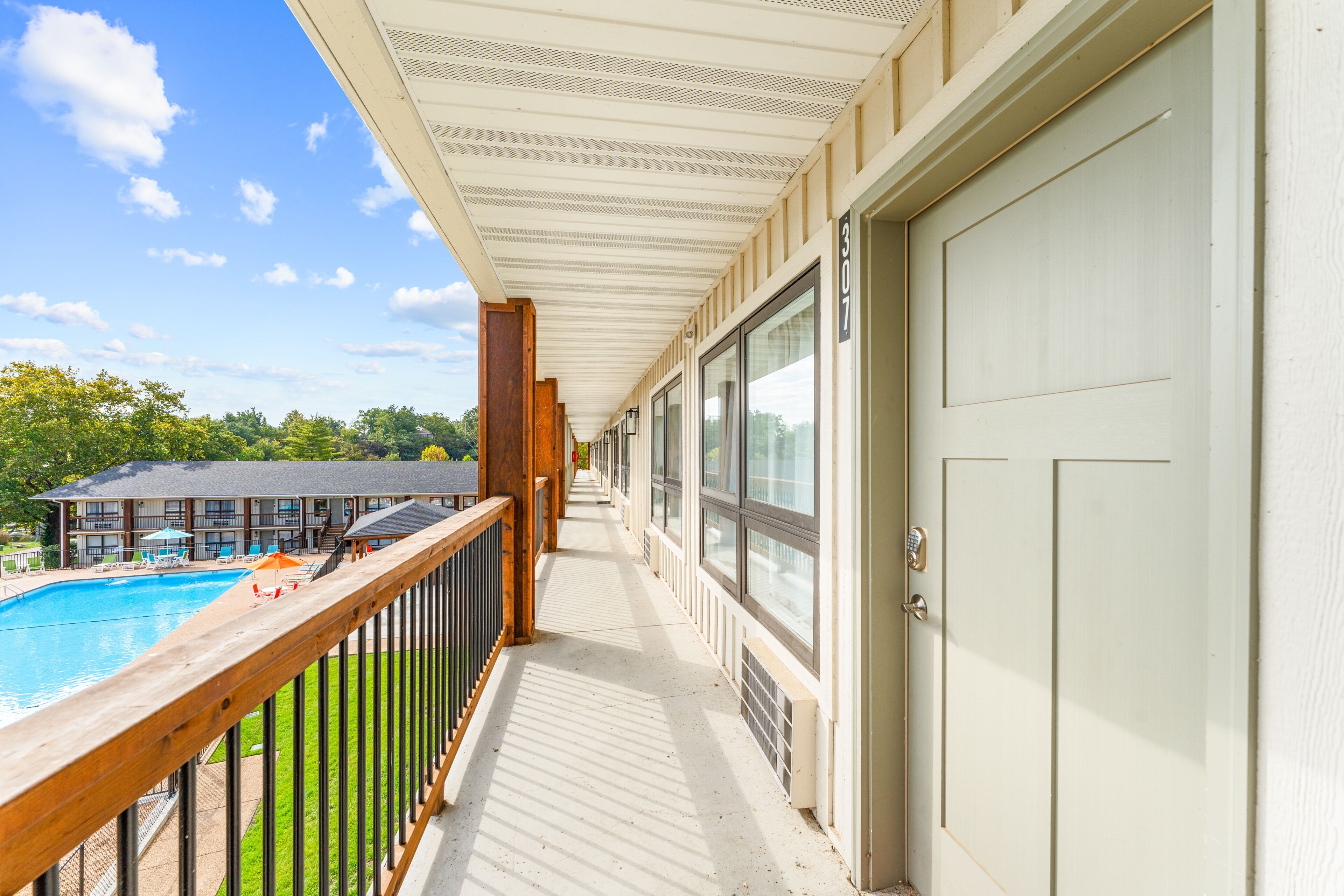A balcony with a pool, wooden railing, and a door with a number.