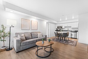 A modern living room with a sofa, two coffee tables, a floor lamp, and a dining area with chairs and a table. - Rc307a- Branson Landing Breeze 2 Bedroom Home (Branson)