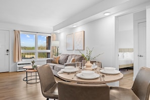 A modern living room with a dining area, a sofa, a bed, and a view of the outdoors. - Rc307a- Branson Landing Breeze 2 Bedroom Home (Branson)