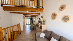 Uma sala de estar ampla com escada de madeira, um sofá e obras de arte decorativas.