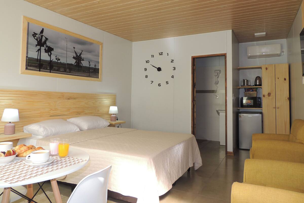 A bedroom with a bed, bedside table, lamp, and a wall clock.