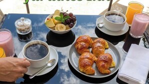 A breakfast table with croissants, fruit, coffee, and juice. - Jardines Inn (Trinidad)