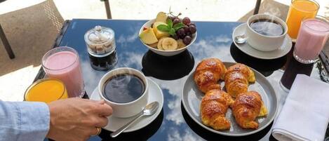A breakfast table with croissants, fruit, coffee, and juice.