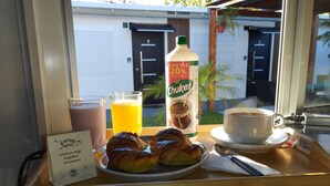 A breakfast tray with croissants, a Chuker drink, a glass of orange juice, and a cup of coffee. - Jardines Inn (Trinidad)