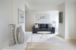 Ein modernes Wohnzimmer mit grauem Sofa, einem weißen Couchtisch und abstrakter Kunst an der Wand.