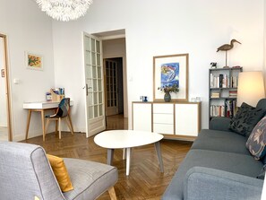 Una sala de estar con un sofá, una mesa de centro, un escritorio y una estantería.