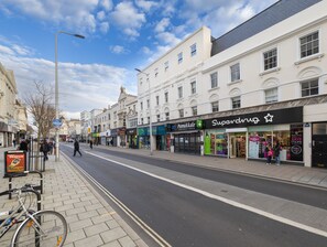 Eine Straße mit Geschäften, darunter eine Apotheke und ein Supermarkt.