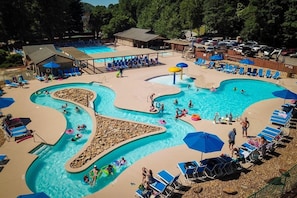 A large outdoor swimming pool with multiple lanes and a water slide, surrounded by lounge chairs and umbrellas. - Shumont Lake Lakefront Home, Resort Access - Casa Bella by Carolina Properties (Lake Lure)