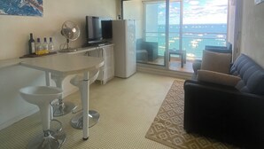 Un espai de vida modern amb cuina, zona de menjador i un balcó amb vista al mar.