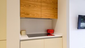 Een keuken met houten kastjes, een wit aanrecht en een klein rood decoratief object.