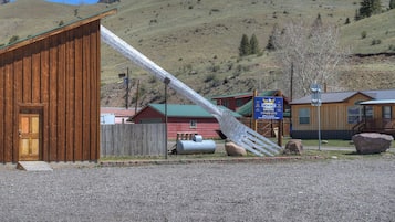 Une cabane avec une façade en bois, un escalier en métal et une enseigne indiquant « CABANES » et « CABANES POUR RAQUETTES ».