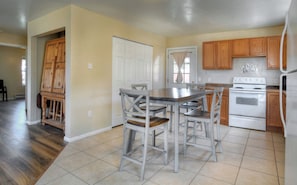 A kitchen with wooden cabinets, a white stove, and a dining table with chairs.