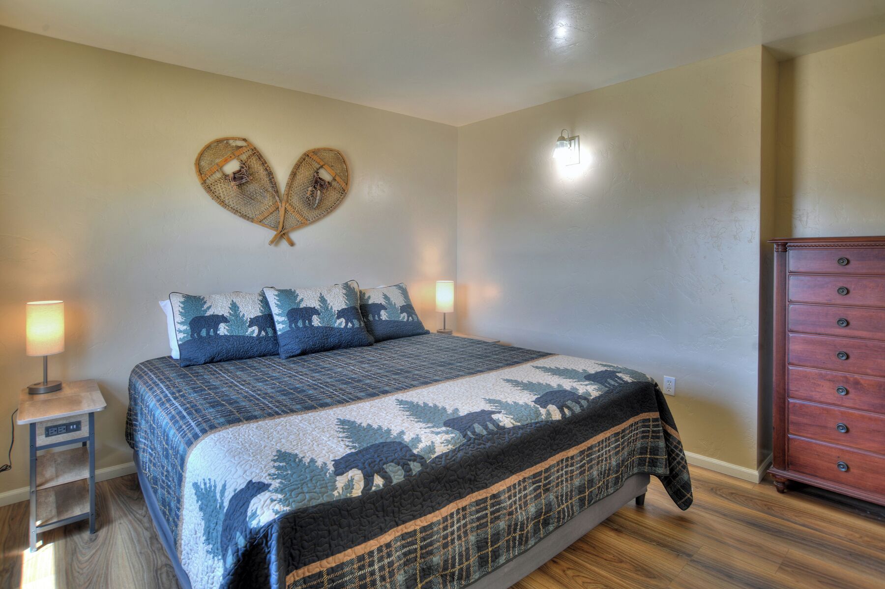 Une chambre à coucher comprenant un lit, deux lampes de chevet, une commode et un décor mural en forme de cœur.