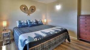 A bedroom with a bed, two bedside lamps, a dresser, and a wall-mounted heart-shaped decoration. - New Listing! Quaint Affordable Cabin | Walkable to Downtown Creede (Creede)