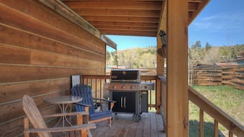 Une terrasse en bois avec un barbecue, une table et deux chaises.