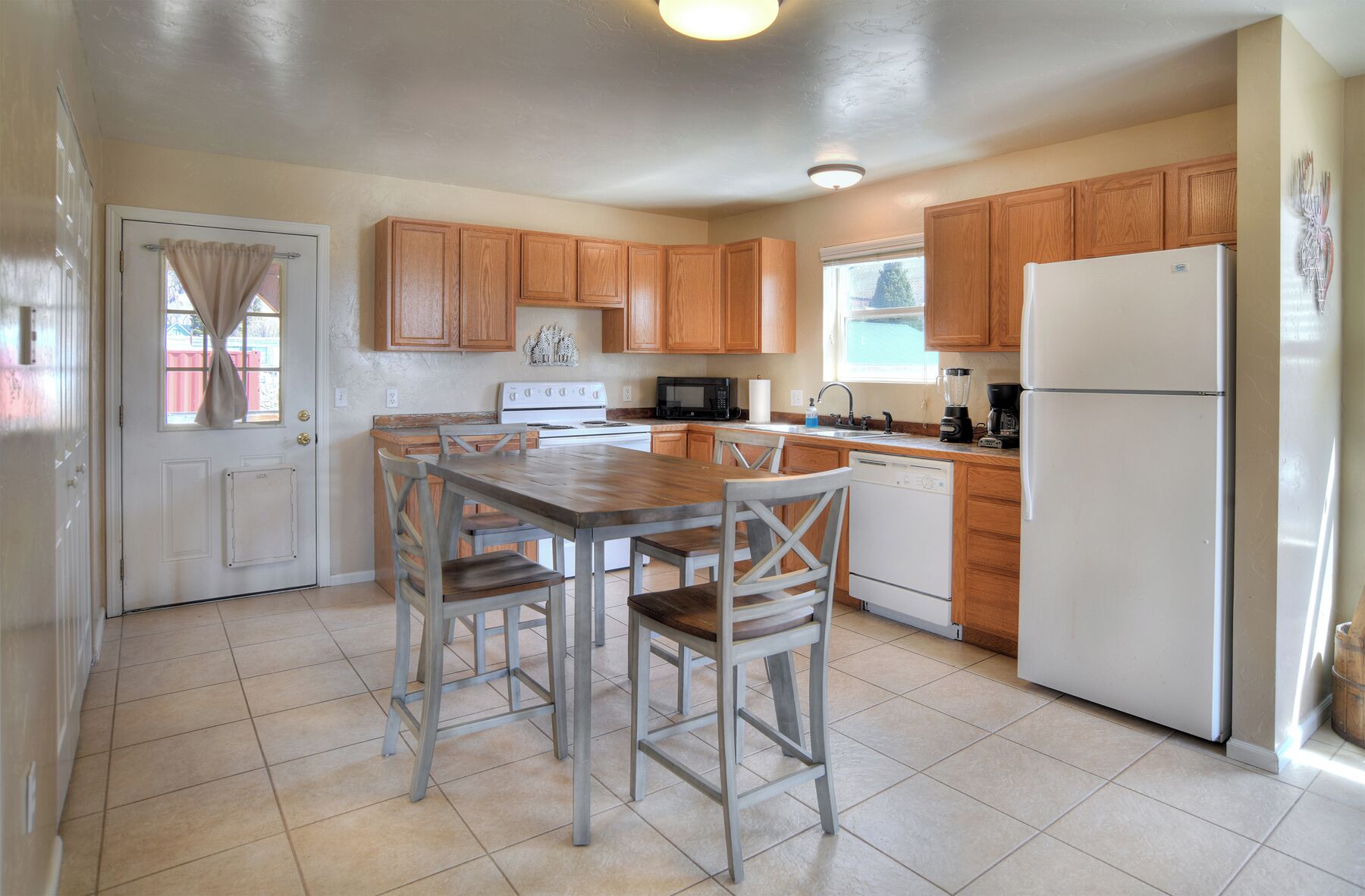 Une cuisine avec des meubles de rangement en bois, un réfrigérateur blanc, une cuisinière et une table à manger avec des chaises.