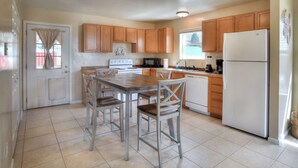 A kitchen with wooden cabinets, a white refrigerator, a stove, and a dining table with chairs. - New Listing! Quaint Affordable Cabin | Walkable to Downtown Creede (Creede)