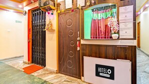 A hotel reception area with a wooden reception desk, a closed black gate, and a red mat at the entrance. - Deluxe With Ganga View Green Guest House (Shrirampur)
