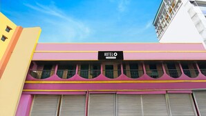 A hotel with a pink facade, a sign reading 'HOTEL O & Company Service,' and closed shutters. - Deluxe With Ganga View Green Guest House (Shrirampur)