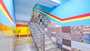A staircase with a metal handrail, tiled walls, and potted plants. - Deluxe With Ganga View Green Guest House (Shrirampur)