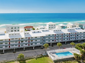 Un hotel con varios pisos, piscina y vista al océano.