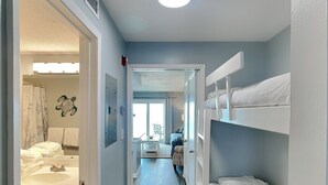 Een smalle gang met stapelbedden aan de ene kant en een badkamer aan de andere kant.