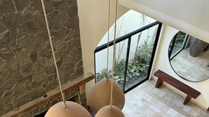 Ein modernes Wohnzimmer mit Kamin aus Stein, kugelförmigen Pendelleuchten, einer Couch und einem gemusterten Teppich.