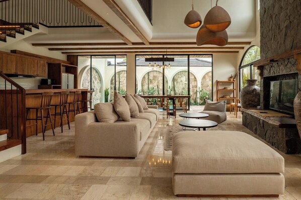 A spacious living area with a sofa, ottoman, and dining area. - Spacious 4-bedroom Private villa in charming in Kuta with Swimming Pools (Tuban Kuta)