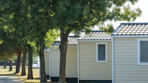 A row of mobile homes with a paved path and trees in the background. - Premium Family Base by Sea (Brtonigla)