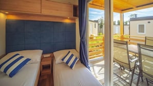 A room with two beds, a wooden ceiling, and a balcony with a view of the outside. - Premium Family Base by Sea (Brtonigla)