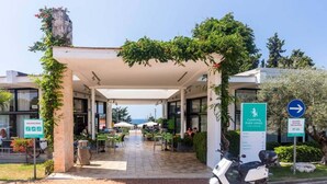 A covered outdoor area with tables and chairs, a scooter, and signs indicating a walking zone and camping park. - Premium Family Base by Sea (Brtonigla)