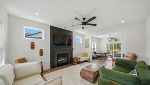 A spacious living room with a fireplace, a ceiling fan, and a dining area with a table and chairs. - SoKno Retreat, Pool Table, Sunroom, 15 min-Knox, 35-Sevier (Knoxville)