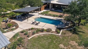 Uma casa moderna com piscina, varanda coberta e vista para a paisagem ao redor.