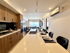 A modern kitchen with a long island, dining area with chairs, and a view to the outside. - Harbor 171 – Oceanview Condo + Rooftop Pool (28th Floor) (Puerto Vallarta)