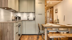 A modern kitchen with a dining area, wooden flooring, and a chandelier. - Appart 5pax | Parking | Balconies | Views (Chamonix-Mont-Blanc)