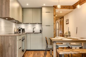 A modern kitchen with a dining area, wooden flooring, and a chandelier. - Appart 5pax | Parking | Balconies | Views (Chamonix-Mont-Blanc)