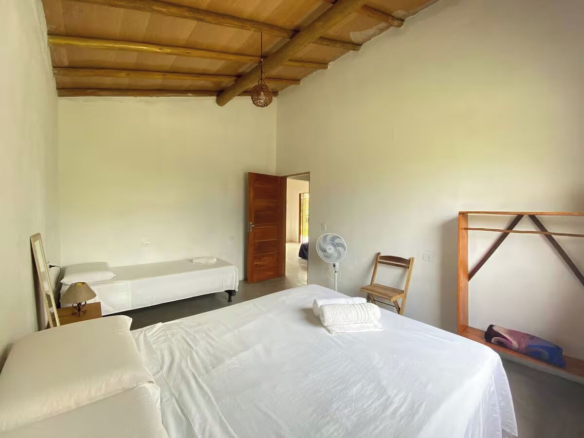 Habitació amb dos llits, un sostre de fusta, un ventilador i una cadira de fusta.