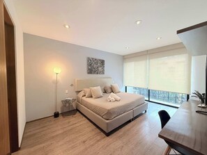 Ein modernes Schlafzimmer mit Bett, Nachttisch, Stehlampe und einem großen Fenster.