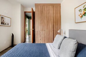 Ein Schlafzimmer mit Bett, Kleiderschrank, einer Tür und einem Wandbild.