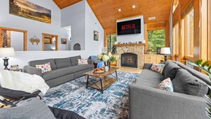 A living room with a fireplace, a television mounted on the wall, and a ceiling fan. - 1st in Sugar/View/EV Charge/Hot Tub/Sauna/Pet Friendly/Sleeps 12/Two Master Bdrs (Sugar Mountain)
