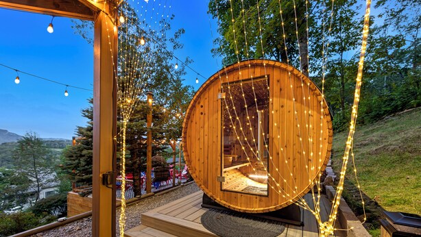 A wooden cabin with a circular door, surrounded by string lights, and a view of the landscape. - 1st in Sugar/View/EV Charge/Hot Tub/Sauna/Pet Friendly/Sleeps 12/Two Master Bdrs (Sugar Mountain)